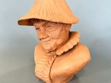 wooden bust of an old man wearing a hat on a table