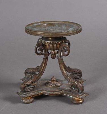 une table ancienne en bronze avec un plateau en verre, sur fond gris