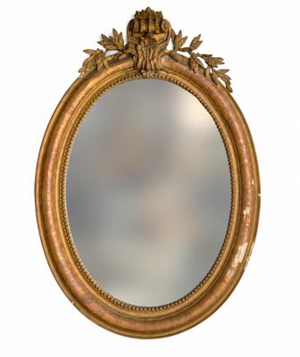 an oval mirror with a gold frame and a flower decoration