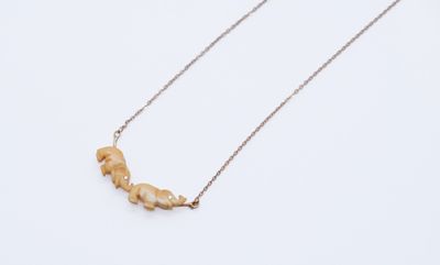 a gold necklace with a small piece of wood on it