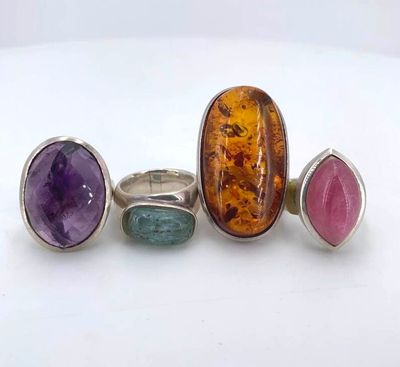 three rings with different colored stones on a white surface