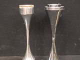 two silver candlesticks sitting next to each other on a table