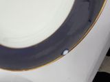 a blue and white plate with a gold rim on a table