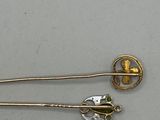 pair of gold and green brooches on a white surface
