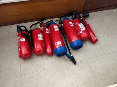 cinq extincteurs alignés sur le sol