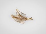 un gros plan d'une broche en feuille d'or sur fond blanc