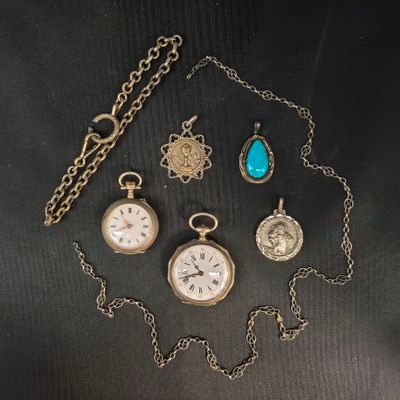 un assortiment de montres de poche et de colliers anciens posés sur un fond noir