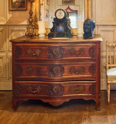 une commode sur laquelle est posée une horloge, dans une pièce