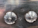 two metal knobs on the side of a metal plate