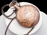 a silver pocket watch on a white plate on a black background