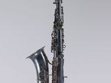 a close up of a saxophone on a white surface with a gray background