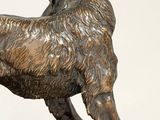 bronze statue of a dog standing on a rock on a white background