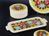 a yellow plate with flowers on it next to a stack of coasters