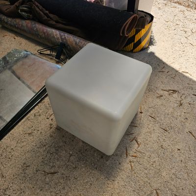 un cube blanc posé par terre à côté d'une cheminée