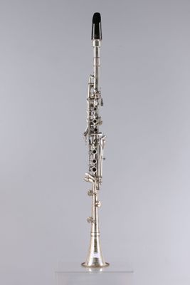 a close up of a silver and black clarinet on a white surface