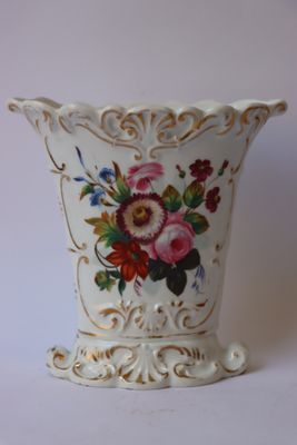 un vase blanc avec des fleurs posé sur une table