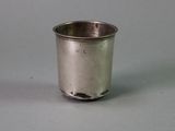 a small silver cup with a handle on a gray surface