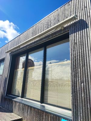 une grande fenêtre équipée de stores, située sur le côté d'un immeuble