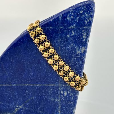 a close up of a gold bracelet on a blue stone