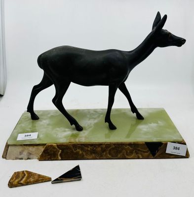statue d'un cerf noir sur un socle vert, à côté d'un triangle