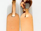 une paire d'étiquettes à bagages en cuir beige sur un fond blanc