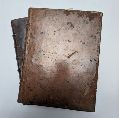 un vieux livre à la couverture marron posé sur une table blanche