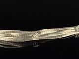 a silver bracelet with diamonds on it on a black surface