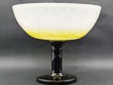 yellow and white glass bowl sitting on top of a black base
