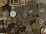 a pile of old coins and a bank note on a table
