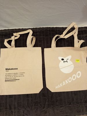 two tote bags sitting on a bed next to each other
