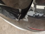 the rear end of a car with a denting dent on it ' s bumper