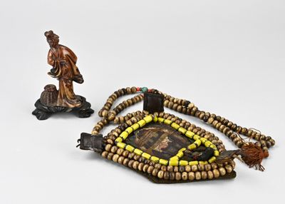 deux morceaux de bois ornés de perles et d'une figurine, posés sur une surface blanche