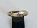 une image représentant une bague en argent posée sur un socle noir, sur une surface blanche