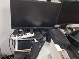 a desk with two monitors, a laptop, a tablet and a game controller
