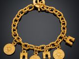 a gold bracelet with five charms and a cross
