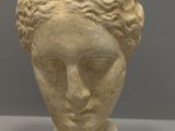 sculpture of a woman ' s head on a stand next to a pair of scissors