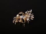 un gros plan d'une broche en or sertie de diamants sur un fond noir