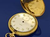 une montre de poche en or posée sur une table bleue
