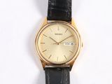 a gold wrist watch on a black leather strap