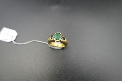 Gros plan sur une bague en or ornée d'une pierre verte