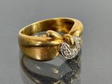 une bague en or sertie d'un diamant, posée sur une table