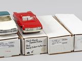 Plusieurs petites voitures sont posées sur des cartons, sur une surface blanche.