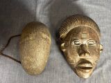 une paire de masques africains et une boule posés sur un tissu blanc
