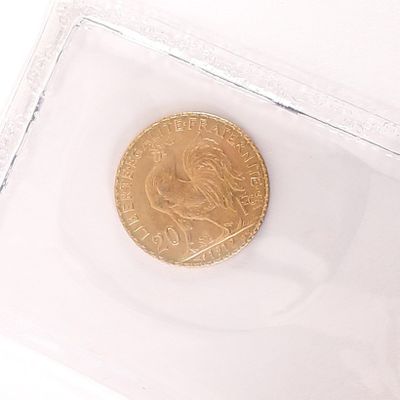 une pièce d'or dans un étui en plastique transparent posé sur une surface blanche