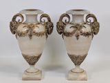 une paire de vases blancs et dorés posés sur une table blanche