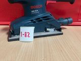 un gros plan d'une ponceuse posée sur une table, avec une boîte rouge en arrière-plan