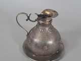 a silver pitcher and a spoon on a table
