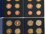 a set of six different coins in a blue box on a white surface