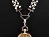 a close up of a necklace with a clock on it