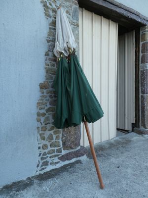 un parapluie vert appuyé contre un mur de pierre